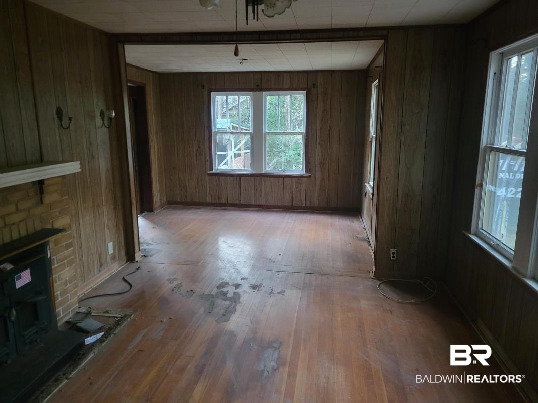 2059 Magnolia Lane Mobile, AL 36605 - Photo 8 of 17 Unfurnished living room with a brick fireplace, wooden walls, and hardwood / wood-style floors