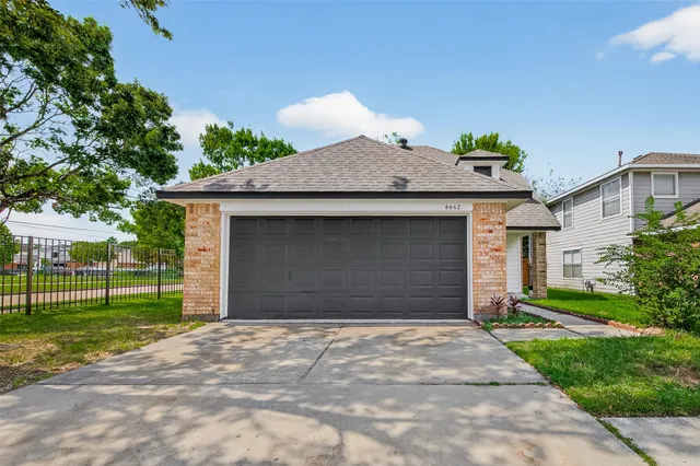 a front view of a house with a garden and trees