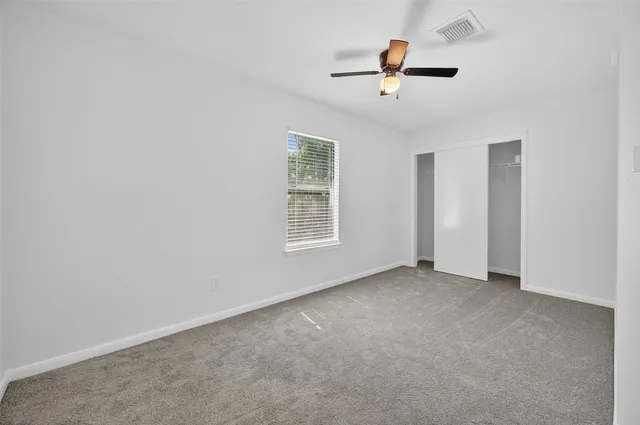 an empty room with ceiling fan and window
