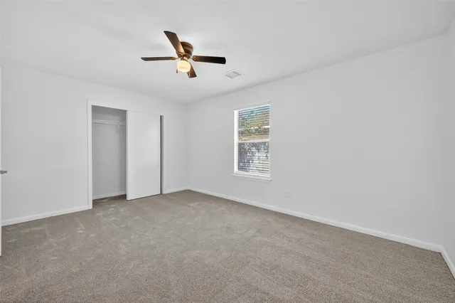 an empty room with windows and fan