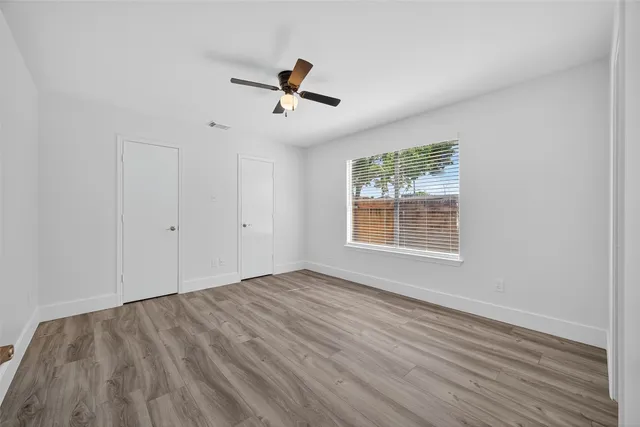 a view of empty room with wooden floor and fan