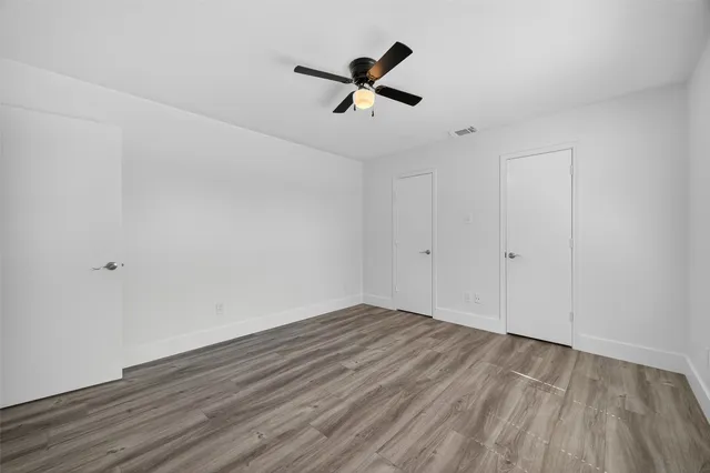 a view of empty room with wooden floor and ceiling fan