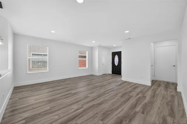 a view of an empty room with wooden floor and windows