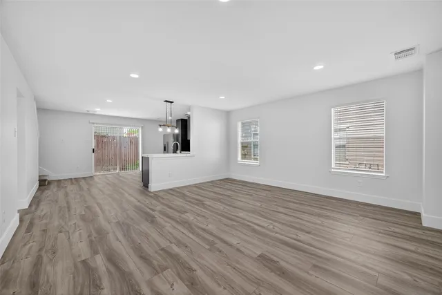 a view of empty room with wooden floor and window