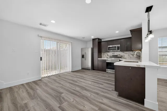 a view of kitchen with stainless steel appliances kitchen island wooden cabinets and entryway
