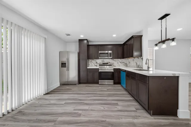 a large kitchen with kitchen island a sink dishwasher a stove and a refrigerator with wooden floor