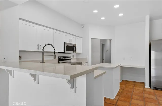 a kitchen with stainless steel appliances kitchen island granite countertop a sink and a refrigerator