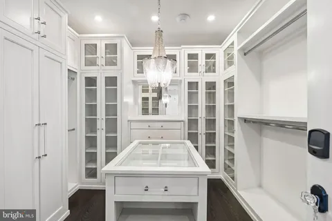 a kitchen with stainless steel appliances kitchen island granite countertop a refrigerator a sink dishwasher and white cabinets with wooden floor