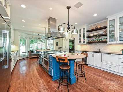 a kitchen with stainless steel appliances a stove center island wooden floor and a window