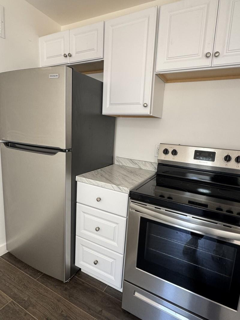 261 Northwest 81st Street, Unit B Miami, FL 33150 - Photo 6 of 12 a kitchen with granite countertop white cabinets and white appliances