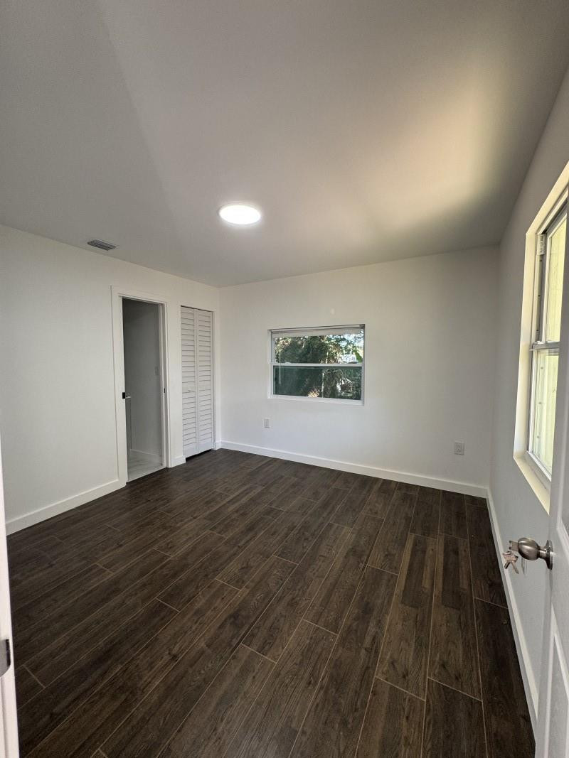 261 Northwest 81st Street, Unit B Miami, FL 33150 - Photo 9 of 12 an empty room with wooden floor and windows