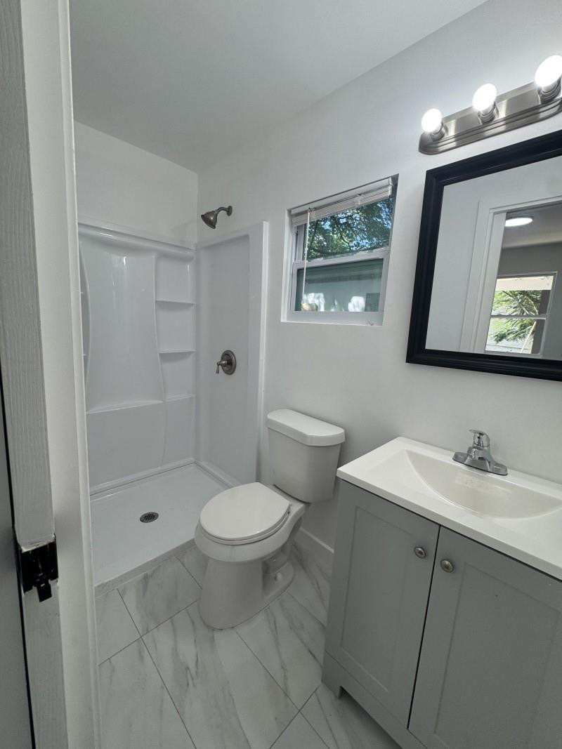 261 Northwest 81st Street, Unit B Miami, FL 33150 - Photo 10 of 12 a bathroom with a toilet a sink a mirror a vanity and shower