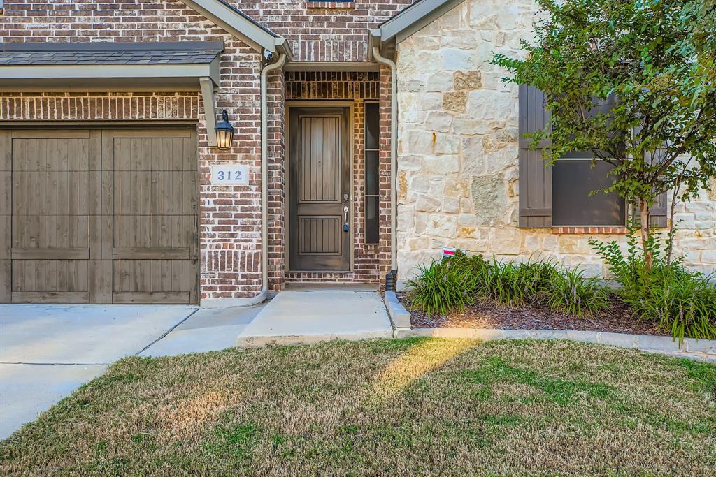 312 Magnolia Drive Oak Point, TX 75068 - Photo 3 of 28 Doorway to property with stone siding, brick siding, and a lawn