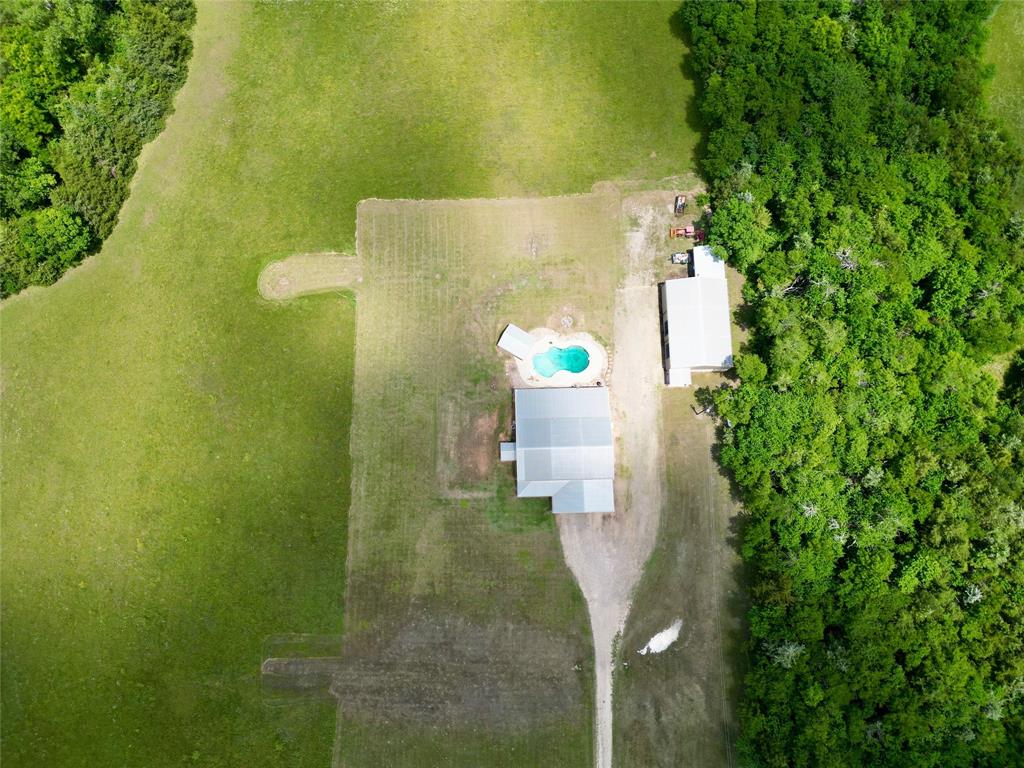 1524 County Road Sumner, TX 75486 - Photo 35 of 35 Expansive property with substantial green space, featuring a main residence with a light-colored roof, a freeform swimming pool, and an additional outbuilding