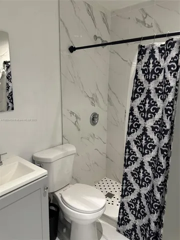 a white toilet sitting next to a shower curtain