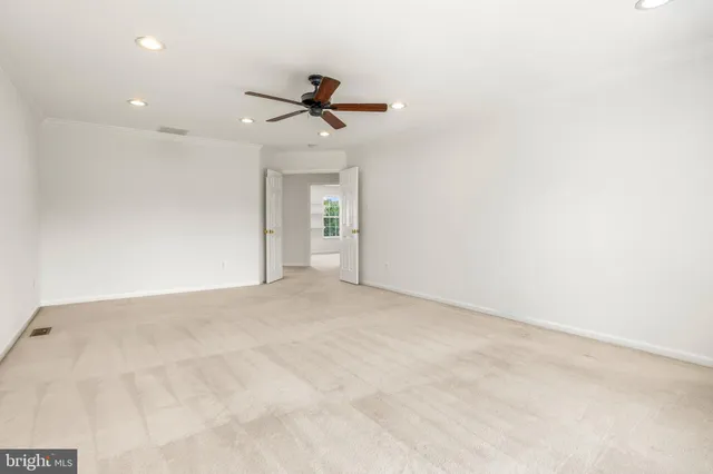 an empty room with a ceiling fan and carpet