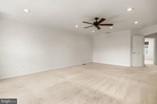 an empty room with a ceiling fan and carpet