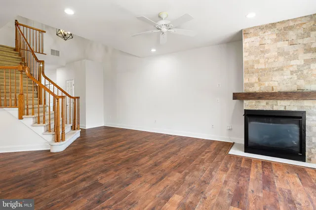 a view of an empty room with wooden floor fireplace and a window