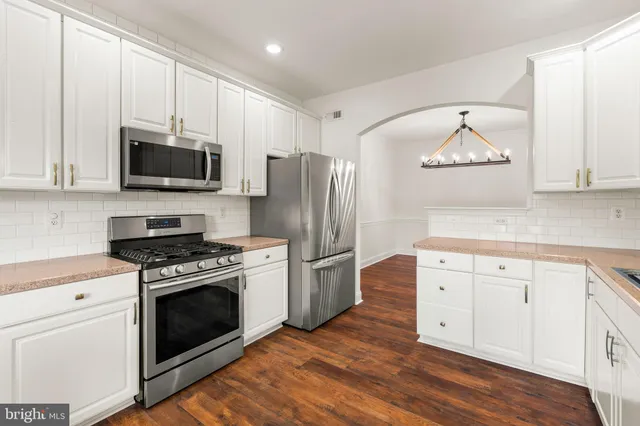 a kitchen with cabinets stainless steel appliances and wooden floor