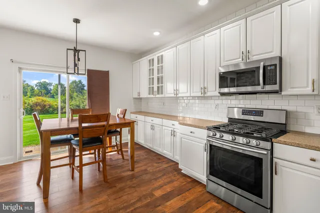 a kitchen with granite countertop wooden floors appliances and dining table