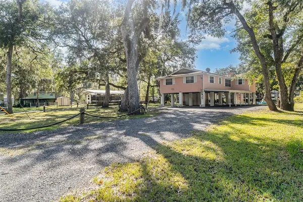 a view of a house with a big yard and large trees