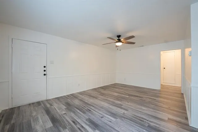a view of a room with wooden floor and a ceiling fan