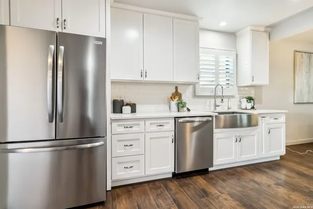 a kitchen with stainless steel appliances a refrigerator a sink cabinets and wooden floor