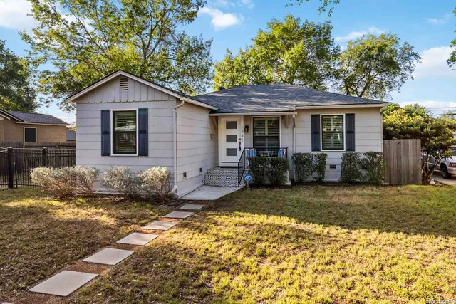 a view of a yard in front of a house with large windows