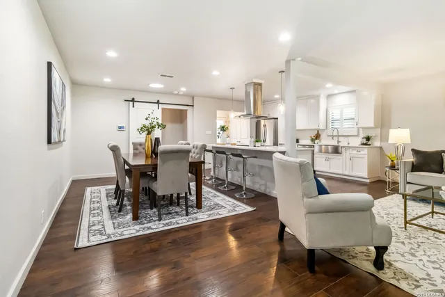 a dining room with furniture wooden floor and a kitchen view