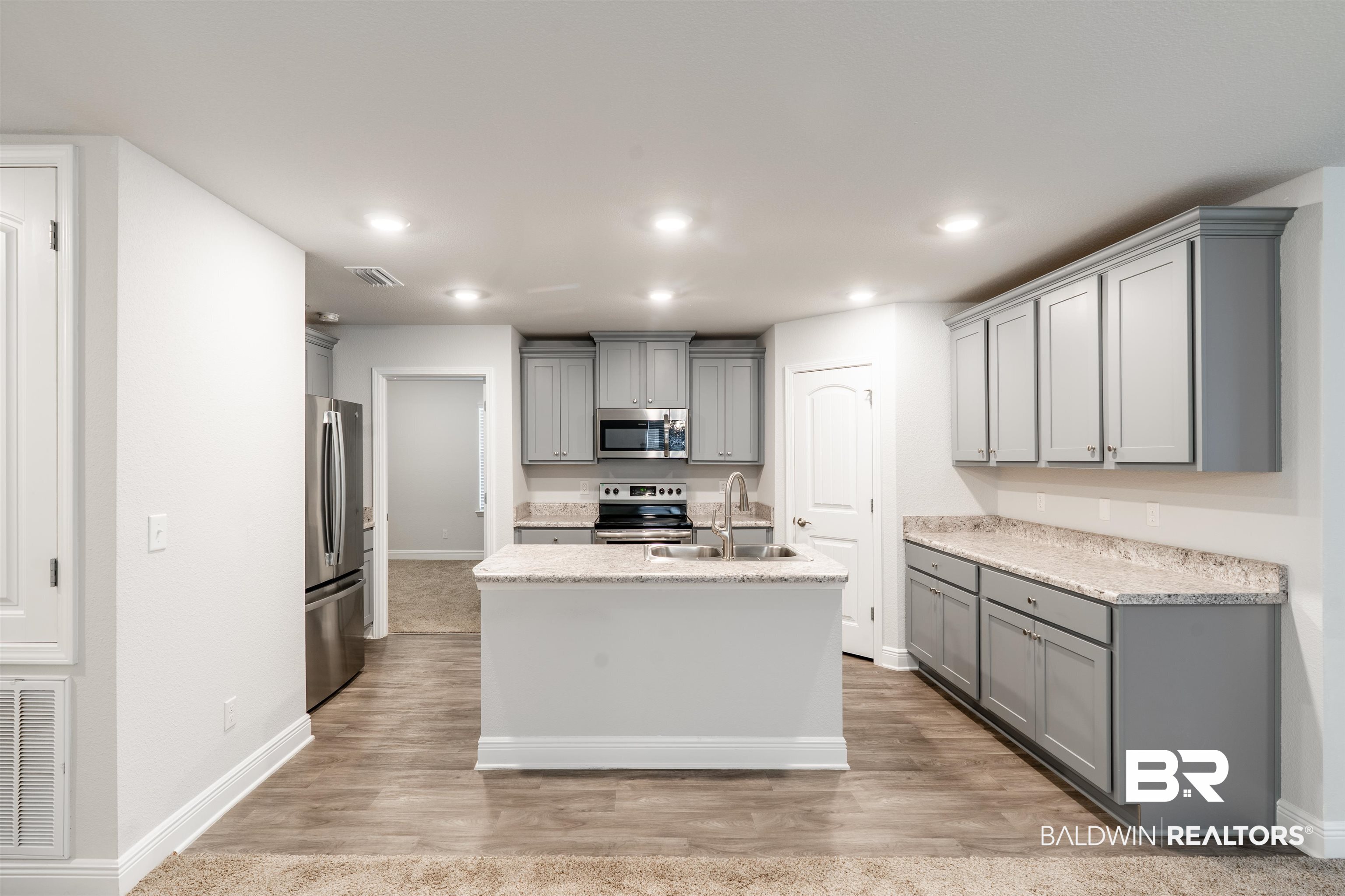 1906 Stonepine Drive South Semmes, AL 36575 - Photo 4 of 30 Kitchen featuring gray cabinetry, appliances with stainless steel finishes, a center island with sink, recessed lighting, and light wood-style flooring