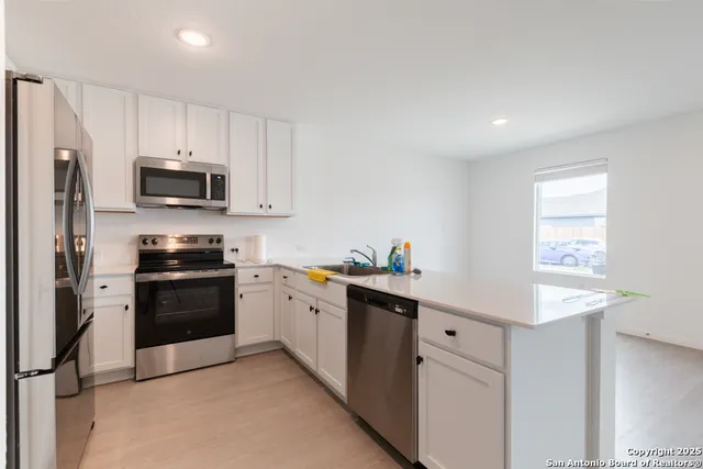 a kitchen with granite countertop white cabinets and stainless steel appliances