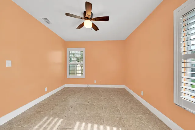 an empty room with windows and fan