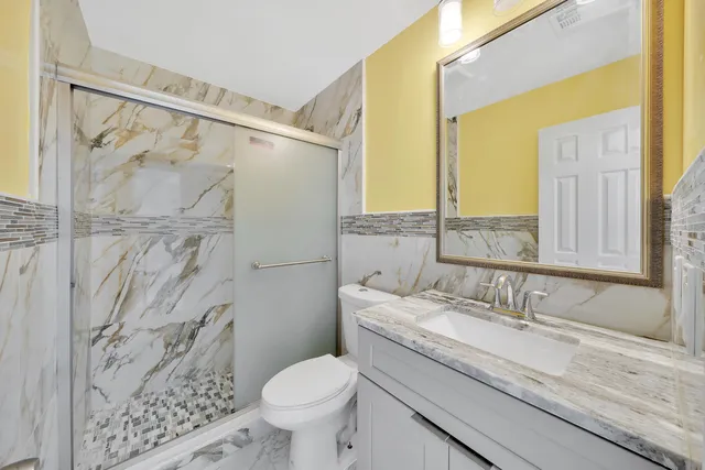 a bathroom with a granite countertop sink a toilet and a shower