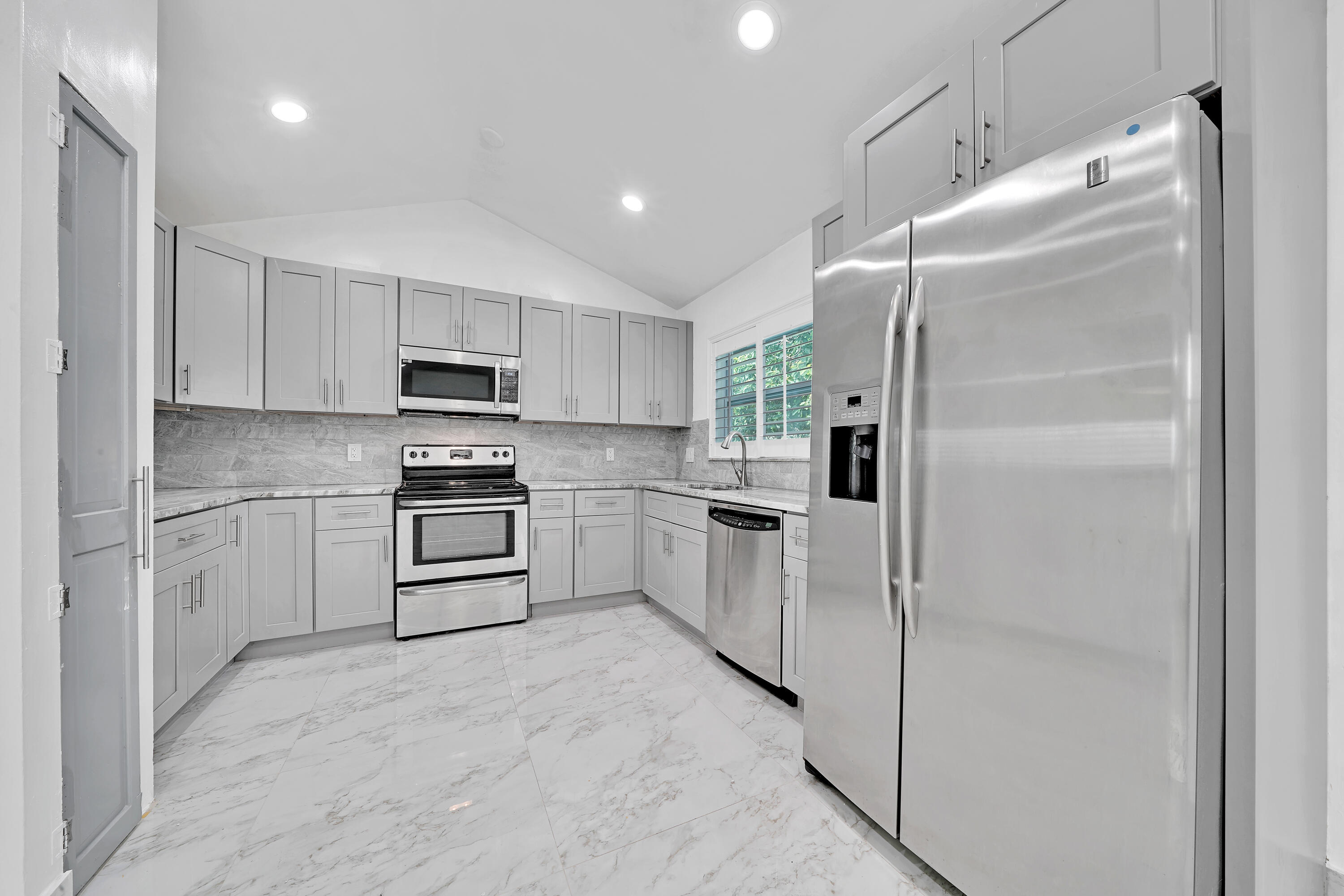 724 Ave Chaumont Delray Beach, FL 33445 - Photo 3 of 35 a kitchen with white cabinets and stainless steel appliances