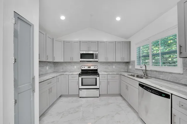 a kitchen with granite countertop white cabinets and white stainless steel appliances