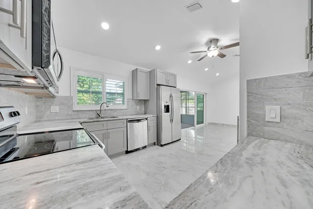 a large kitchen with stainless steel appliances kitchen island granite countertop a sink and cabinets