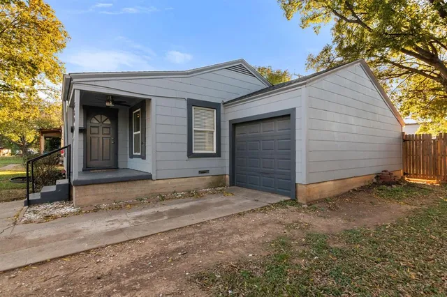 a view of house with garage and large tree