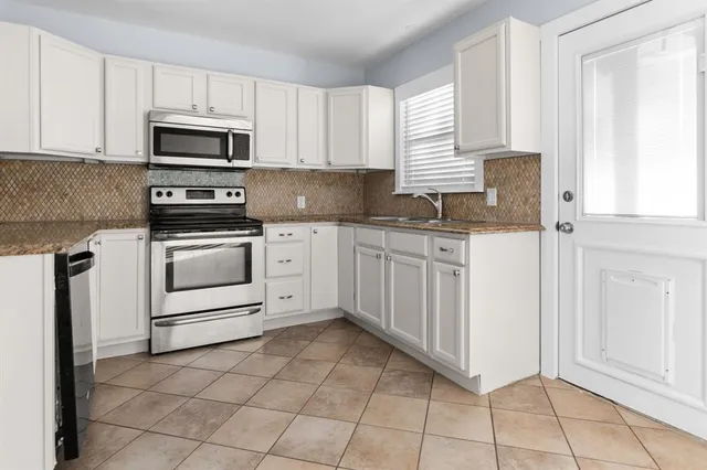 a kitchen with granite countertop white cabinets stainless steel appliances and sink
