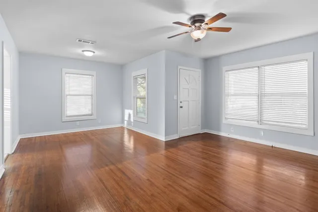 a view of an empty room with window and wooden floor