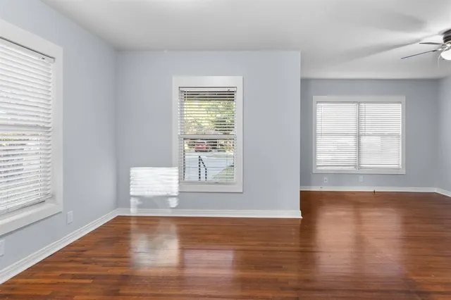 an empty room with wooden floor and windows