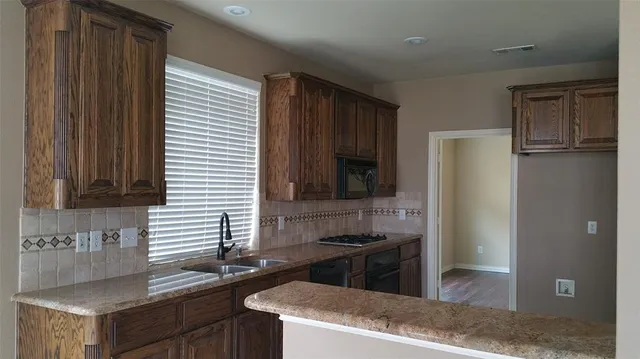 a kitchen with granite countertop a sink and a refrigerator