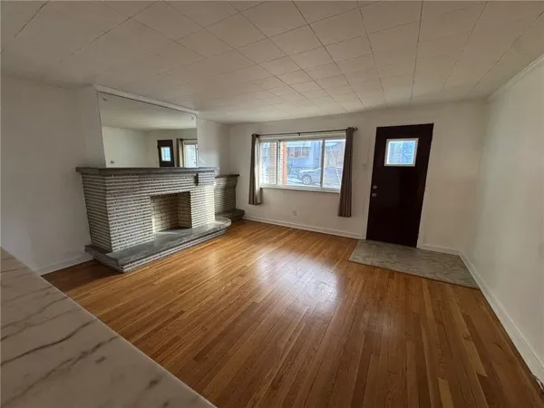 an empty room with wooden floor fireplace and windows
