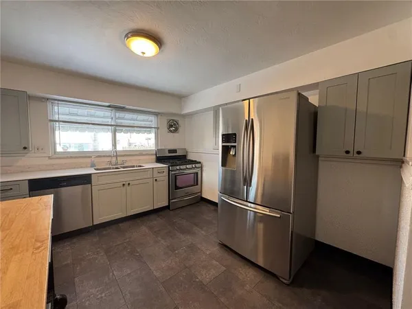 a kitchen with granite countertop stainless steel appliances a refrigerator cabinets and a window