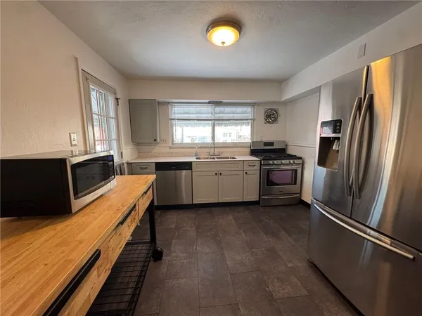 a kitchen with granite countertop stainless steel appliances a sink stove refrigerator and cabinets