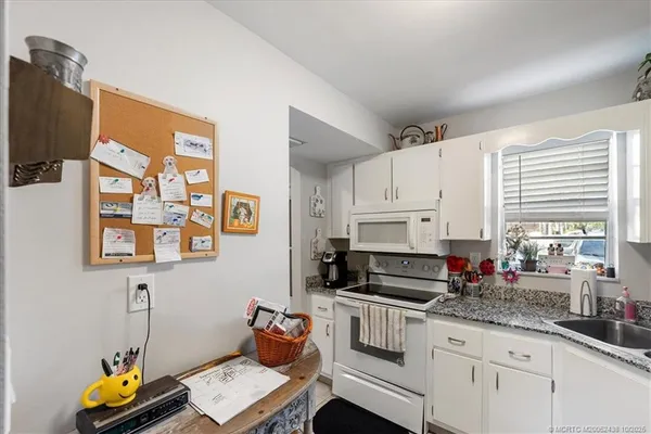 a kitchen with granite countertop a stove a sink and white cabinets