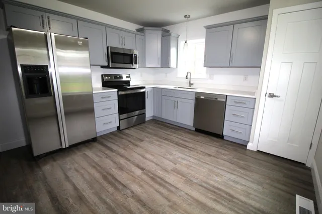 a kitchen with a refrigerator stove top oven and sink