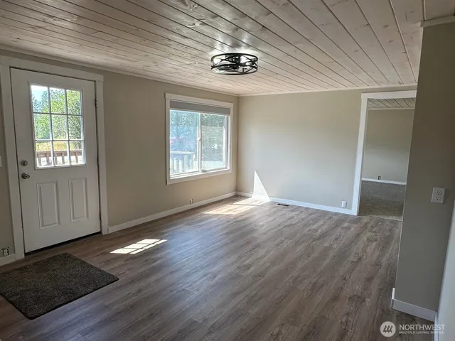 an empty room with wooden floor cabinet and windows
