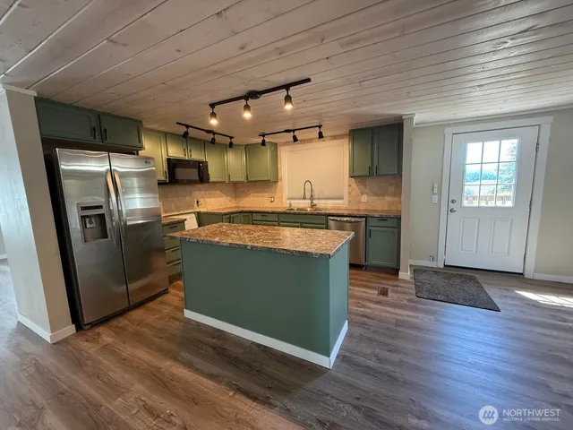 a kitchen with stainless steel appliances granite countertop a sink a stove a refrigerator and a microwave