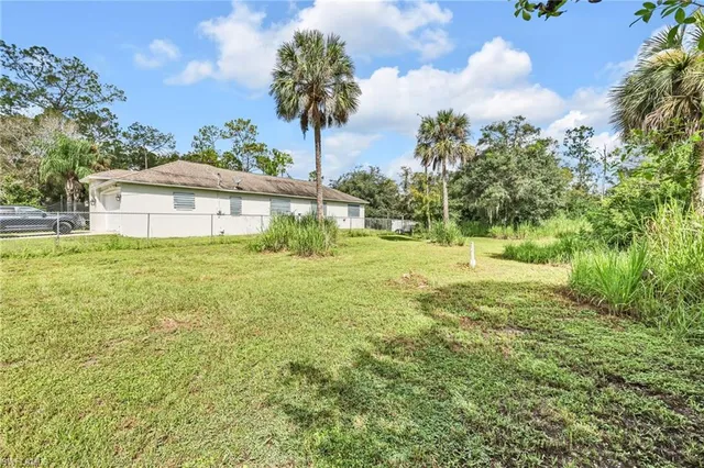 a view of a house with a yard and palm trees