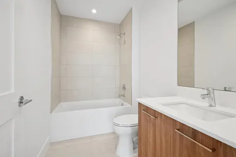 a bathroom with a bathtub shower sink vanity and toilet